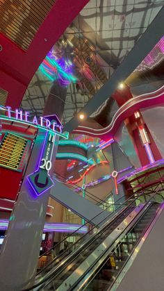 an escalator in a large building with neon lights