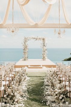 an outdoor ceremony setup with white flowers and greenery on the aisle, overlooking the ocean