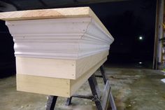 a wooden beehive sitting on top of a metal stand in a garage at night