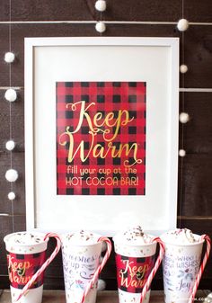 three ice cream cups with candy canes in front of a framed sign that says keep warm