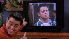 the young man is smiling and pointing his finger up in front of an old tv