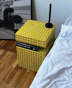 a yellow and white box sitting on top of a bed next to a black candle