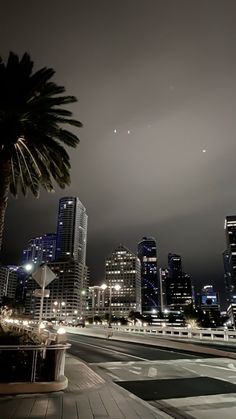 the city skyline is lit up at night with an airplane in the sky over it