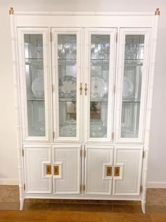 a white china cabinet with glass doors and gold handles