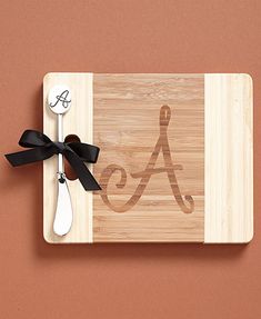 a wooden cutting board with a black bow on it and a spoon in front of it