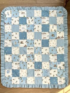 a blue and white quilted placemat with animals on it, sitting on a wooden floor