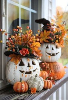 two pumpkins decorated with flowers and jack - o'- lanterns on a window sill