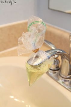 a sink with a plastic bag hanging from it's faucet next to a soap dispenser