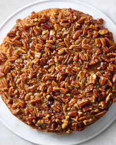 a pecan pie on a white plate with some pecans in the crusting