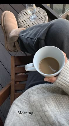 a person sitting on a chair holding a cup of coffee