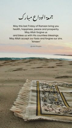 a blanket laying on top of a sandy beach next to the ocean with an islamic quote