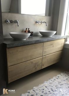 two white bowls sit on top of a wooden vanity