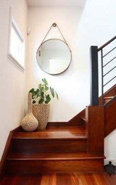 two vases with plants sit on the stairs next to a mirror and door way