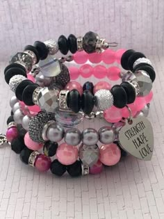 To celebrate a survivor or encourage someone currently struggling with Cancer- this memory wire wrap bracelet is made with a stunning variety of glass and acrylic beads in pinks, silver, gray & black. The hand stamped charm says "Strength, Love, Hope and includes the cancer ribbon". **all items are hand made and one of a kind. Colors will all be alike, but I cannot guarantee an identical pattern of beads. Body Jewelry Diy, Girly Bracelets, Diy Kandi Bracelets, Wire Wrap Bracelet, Crystal Bead Jewelry, Wrist Jewelry, Bead Charms Diy, Diy Bracelet Designs