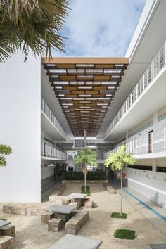 an empty courtyard with benches and tables under a canopy over the area that is surrounded by palm trees