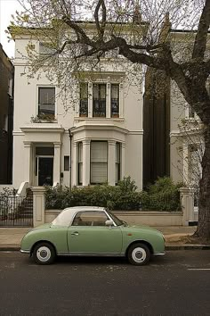 a green car parked in front of a white house