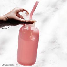 a hand holding a pink water bottle with a straw in it