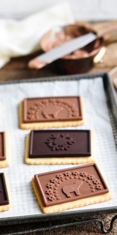 four cookies on a baking sheet with chocolate frosting in the shape of flowers and leaves