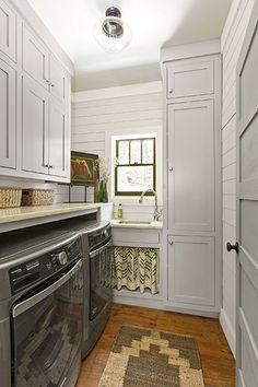 a washer and dryer in a small room with white walls, wood flooring and cabinets