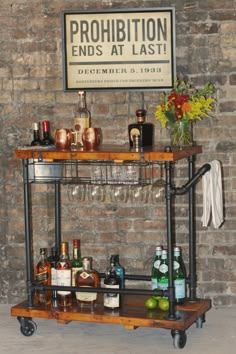 a bar cart with liquor bottles and glasses on it in front of a brick wall