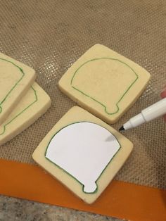 someone is cutting out some cookies with a sharpie on top and another cookie in the background