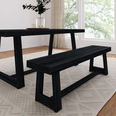 a black table and bench in front of a window with white rug on the floor