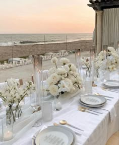 the table is set with white flowers and place settings