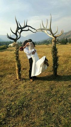 a bride and groom kissing under an antler arch