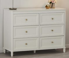 a white dresser with flowers on top of it