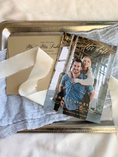 a couple's wedding photos are laying on top of a silver tray with white fabric