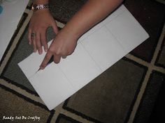 a person cutting paper with a knife on top of the floor next to a piece of paper