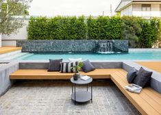 an outdoor seating area next to a pool with water fall in the backround