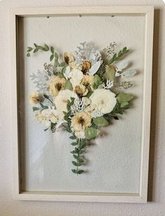 an arrangement of flowers is displayed in a white frame