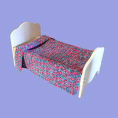 a small bed with a colorful blanket on it's headboard and foot board