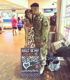 a man and woman standing next to each other holding a sign that says half of my heart is no longer deployed