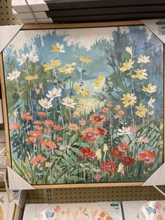 a painting on display in a store with flowers painted on the wall and plates below it