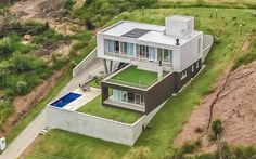 an aerial view of a modern house in the middle of a grassy area with a pool