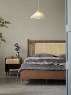 a bedroom with a bed, nightstand and plant in the corner on the wall next to it