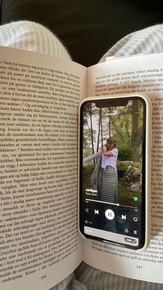 an open book with the image of a woman taking a photo on her cell phone