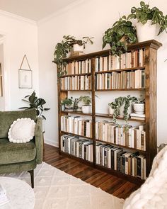 a living room filled with lots of books and plants on top of a book shelf