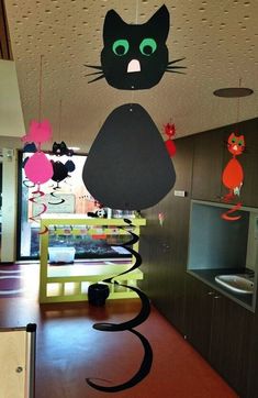 a black cat hanging from the ceiling in a room with many decorations on it's walls