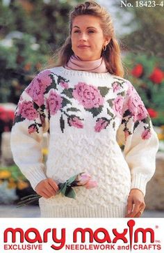 a woman wearing a sweater with flowers on it and holding a flower in her hand