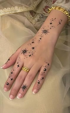 a woman's hand with stars and moon tattoos on it