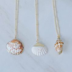 Dive into the deep blue of summer fashion with these gorgeous gold seashell necklaces! Walk the beach in style with perfect accessories that blend the beauty of the sea with the luxury of shimmering gold. Wave goodbye to basic jewelry and make a statement with these stunning necklaces! Gold-detailed seashell charms on a 14k gold plated satellite chain. Necklaces are 16 inches in length and include a 2-inch extender. Ocean-inspired Gold Pendant Necklace, Elegant Beach Pendant Charm Necklaces, Elegant Pendant Charm Necklaces For The Beach, Elegant Beach Pendant Charm Necklace, Elegant Shell Pendant Necklace For Beach, Elegant Shell Necklace For Summer Beach Occasions, Elegant Pendant Shell Necklace For Beach, Elegant Shell Necklace For Summer Beach, Elegant Shell Necklace For Summer