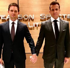 two men in suits are holding hands