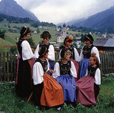 a group of women sitting next to each other on top of a lush green field