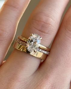 a woman's hand with two gold wedding rings and a diamond ring on her finger