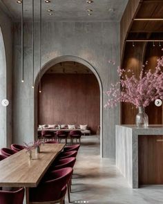 a long table with purple chairs and flowers in vases on the wall next to it