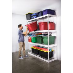 a man standing in front of a white shelving unit with bins and containers on it