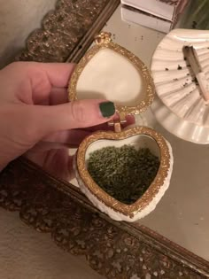 a person holding a heart shaped box filled with green stuff in front of a mirror